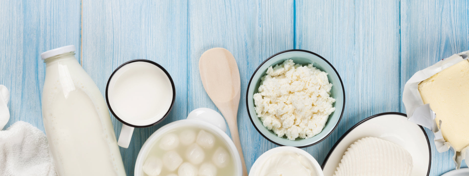 Assorted dairy products including milk, yogurt, and cheese on a blue wooden background